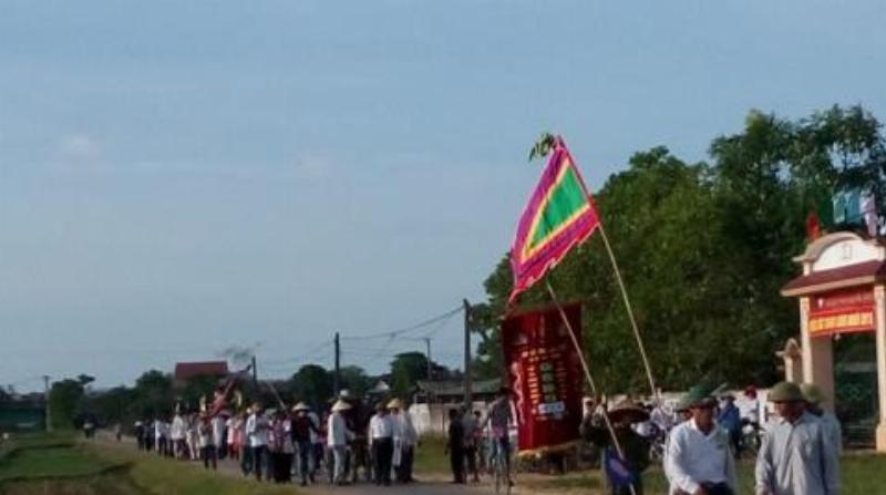 Hình ảnh mâm cúng khai trương được bày biện trang trọng trước một cửa hàng nhỏ, có người đang thực hiện nghi lễ, thể hiện phong tục truyền thống.